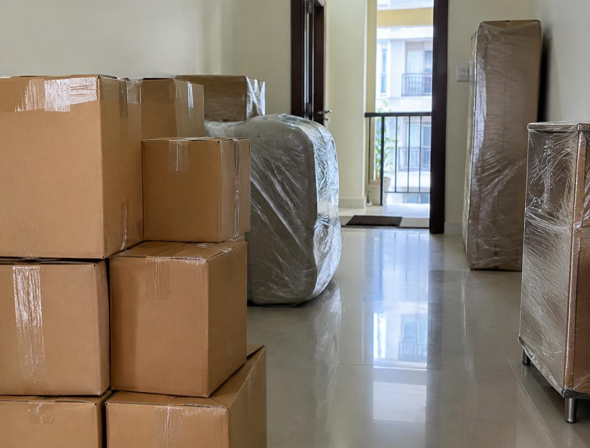 Neatly packed cartons and stretch-wrapped furniture ready for shifting in an apartment hallway